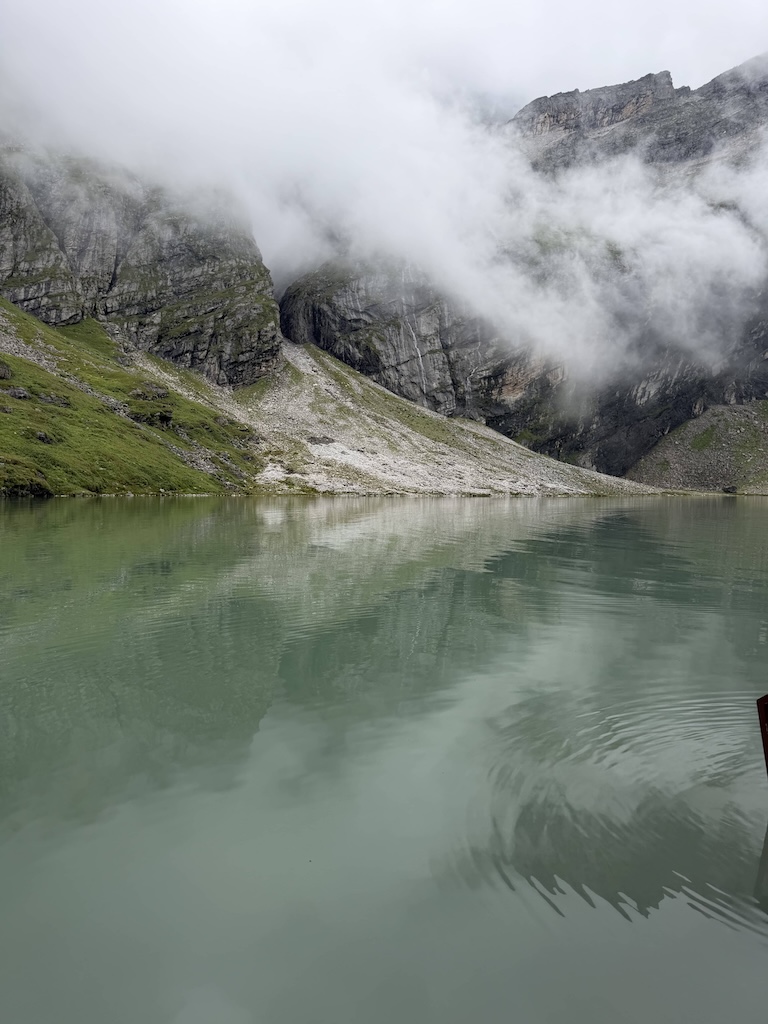 The sarovar — jade-green, still, cloud coming over